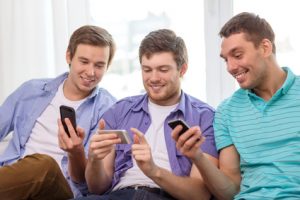 smiling friends with smartphones at home