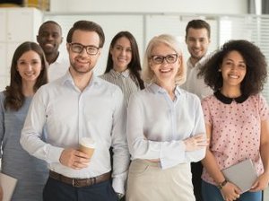 Mitarbeiter stehen in einem modernen Büro und posieren gemeinsam für ein Gruppenfoto.
