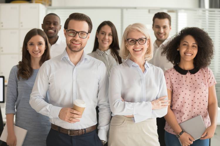 Mach den ersten Schritt – wir freuen uns auf dich! Mitarbeiter stehen in einem modernen Büro und posieren gemeinsam für ein Gruppenfoto.